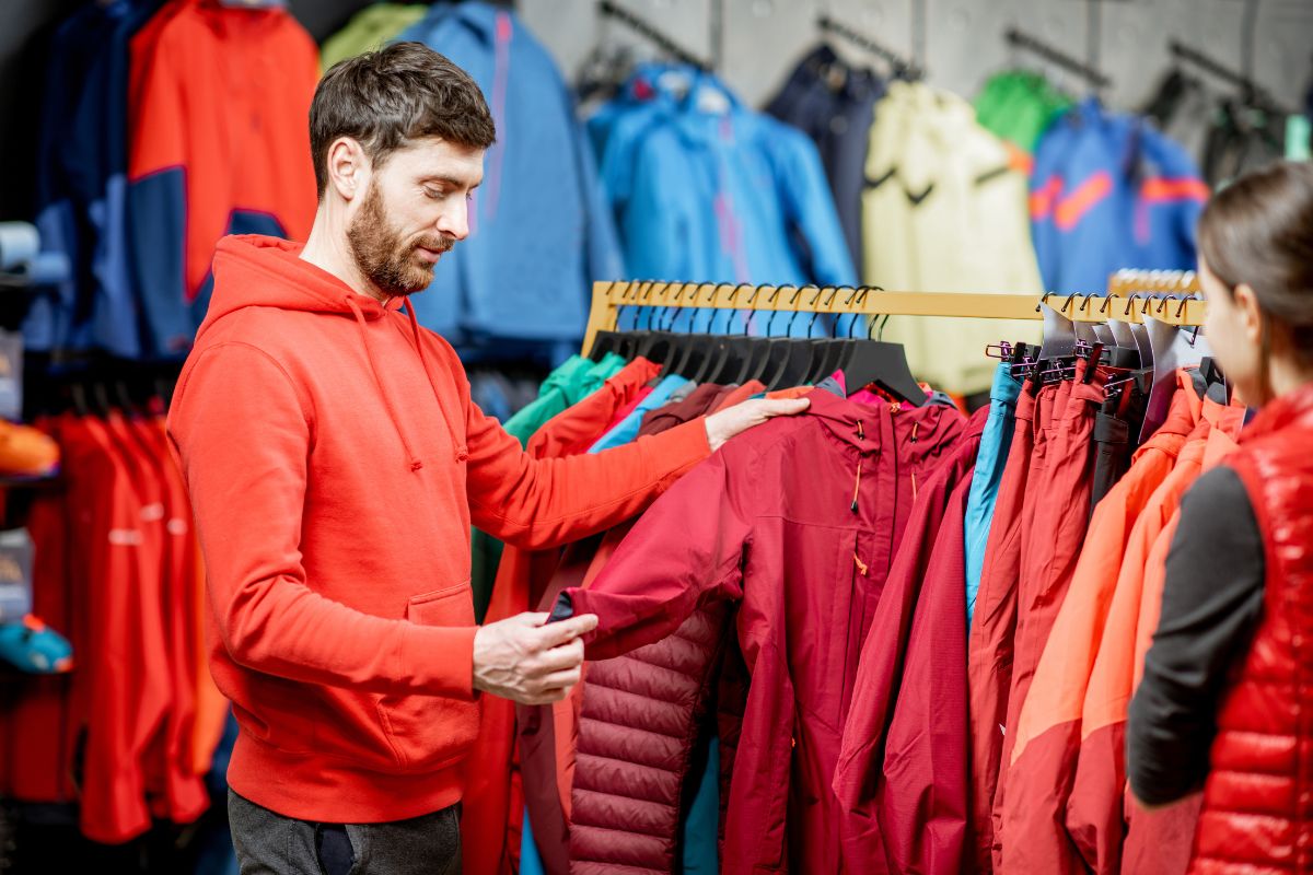 Un homme fait le choix des vêtements de ski dans un magasin.