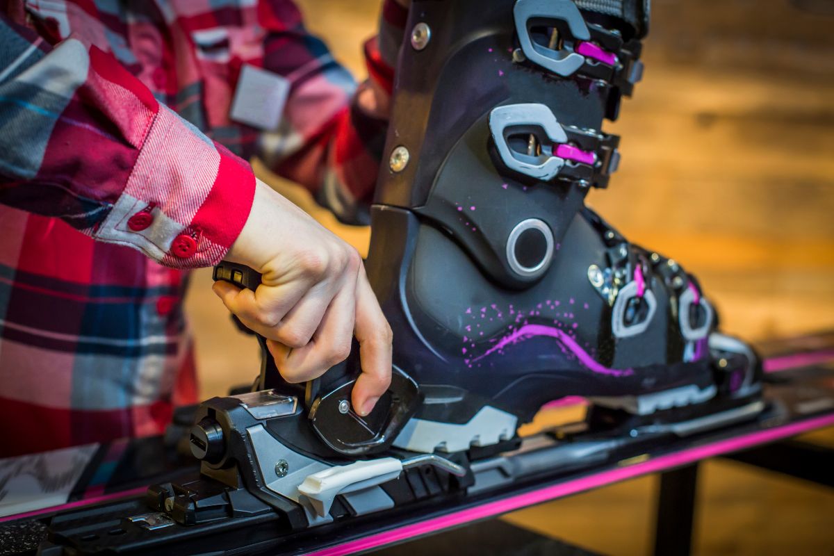 Un sportif expert effectuant le réglage des fixations entre ses skis et ses bottes de ski.